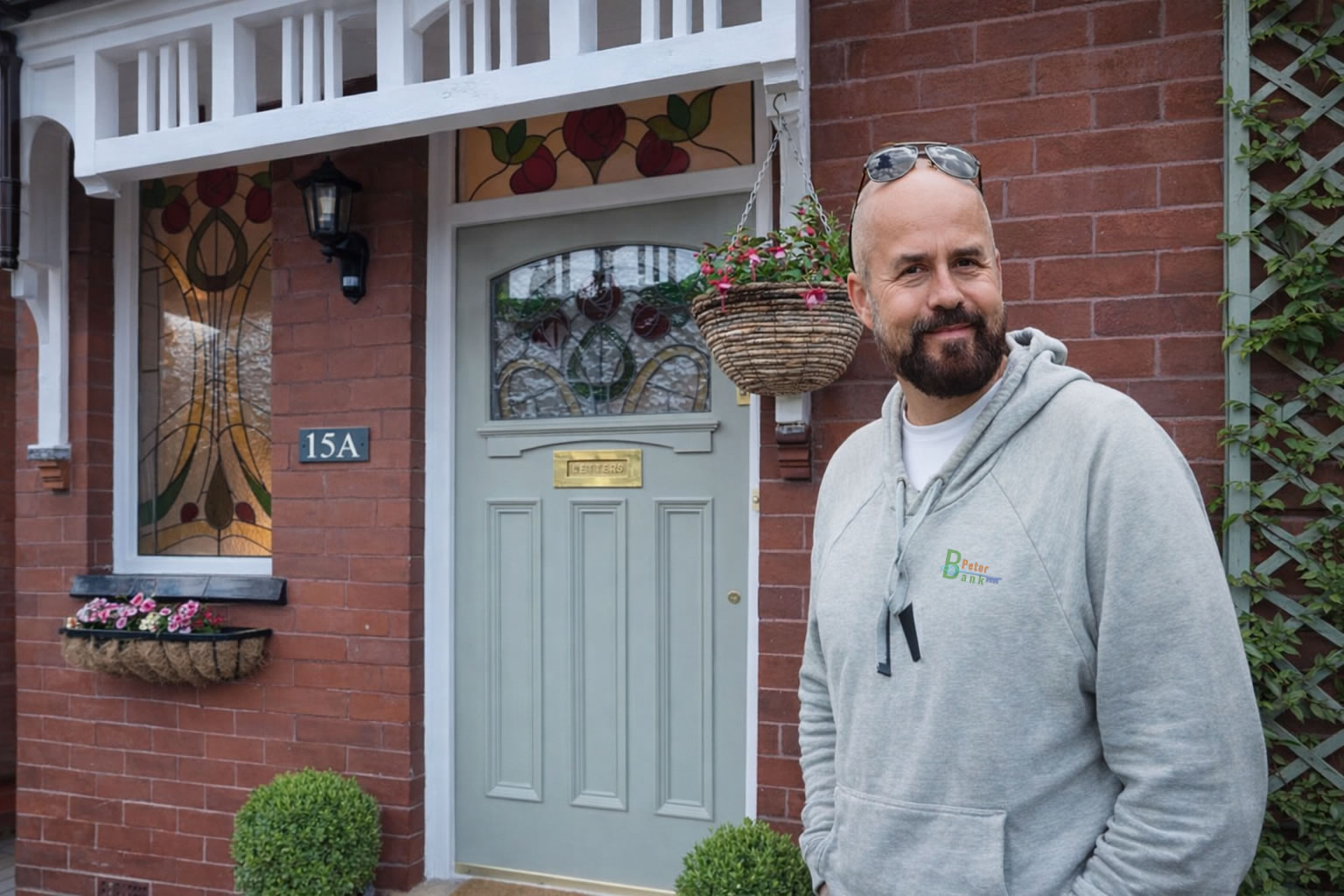 peter standing next to gray door with coloured stained glass window